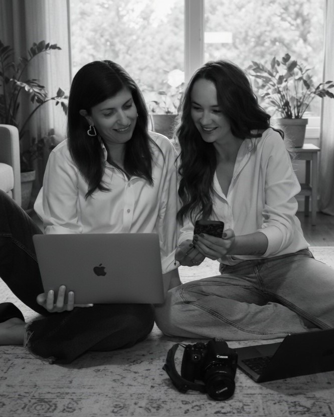 Two founders sitting on a living room floor going over marketing strategy on devices