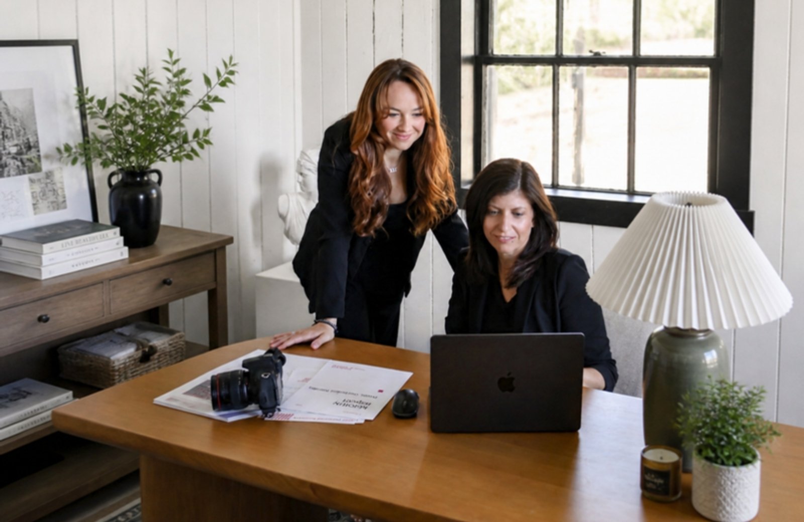 One Eleven Creatives co-founders Veronica Dunn and Sarah Newcomb at their studio desk with a camera and laptop, an example of brand photography for small business