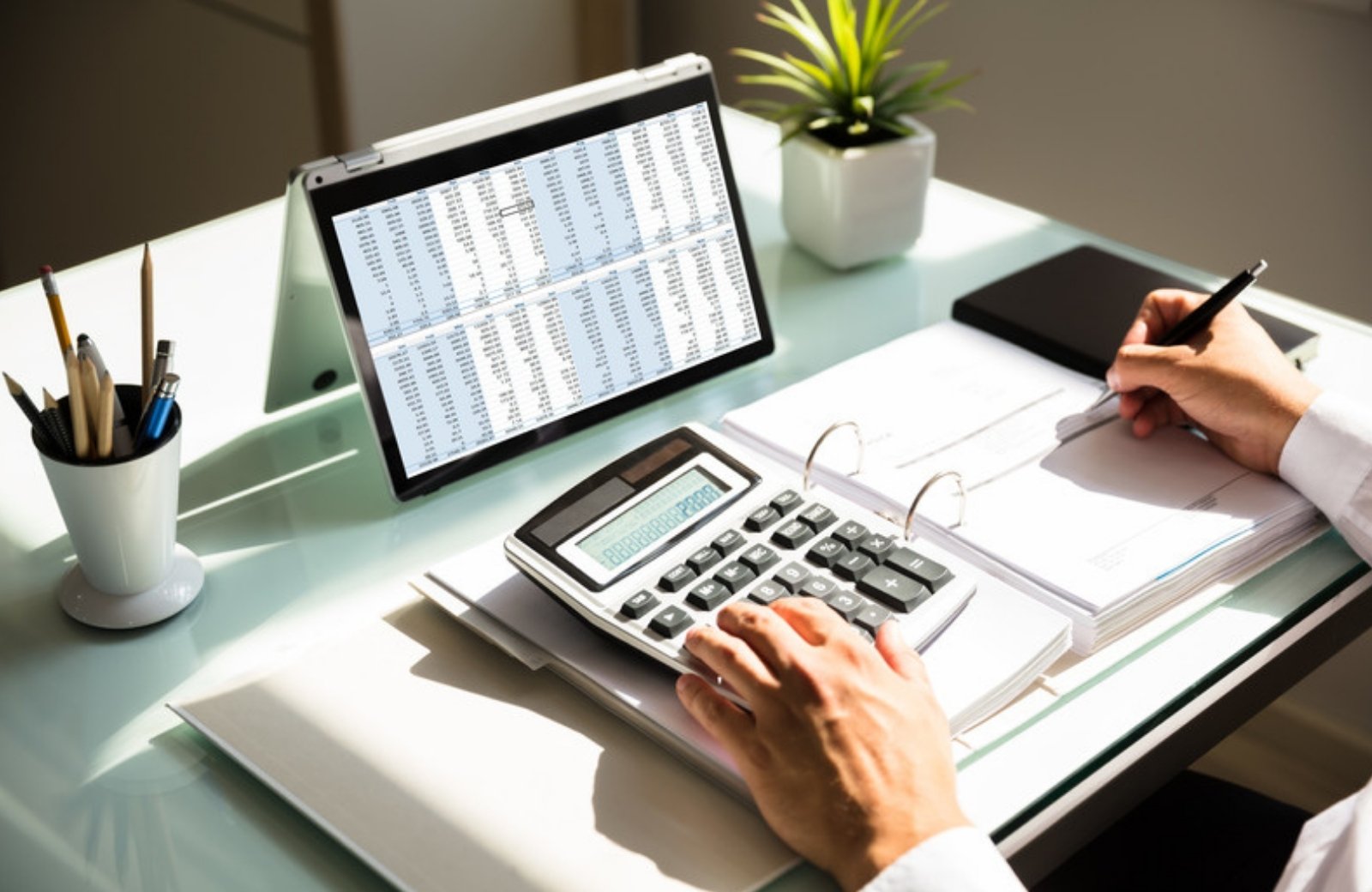 Business owner calculating a marketing budget with a calculator and spreadsheet