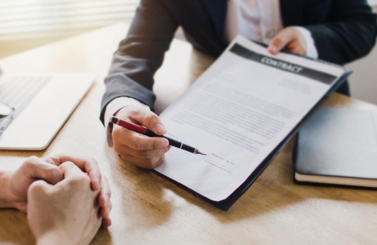 Consultant presenting a contract to a client at a desk Consultant presenting a contract to a client at a desk