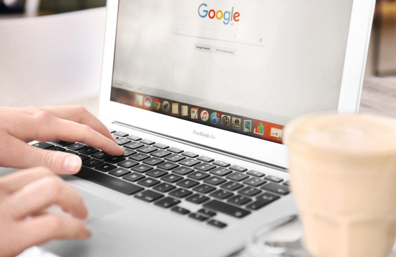 Person typing a search query into Google on a laptop Person typing a search query into Google on a laptop