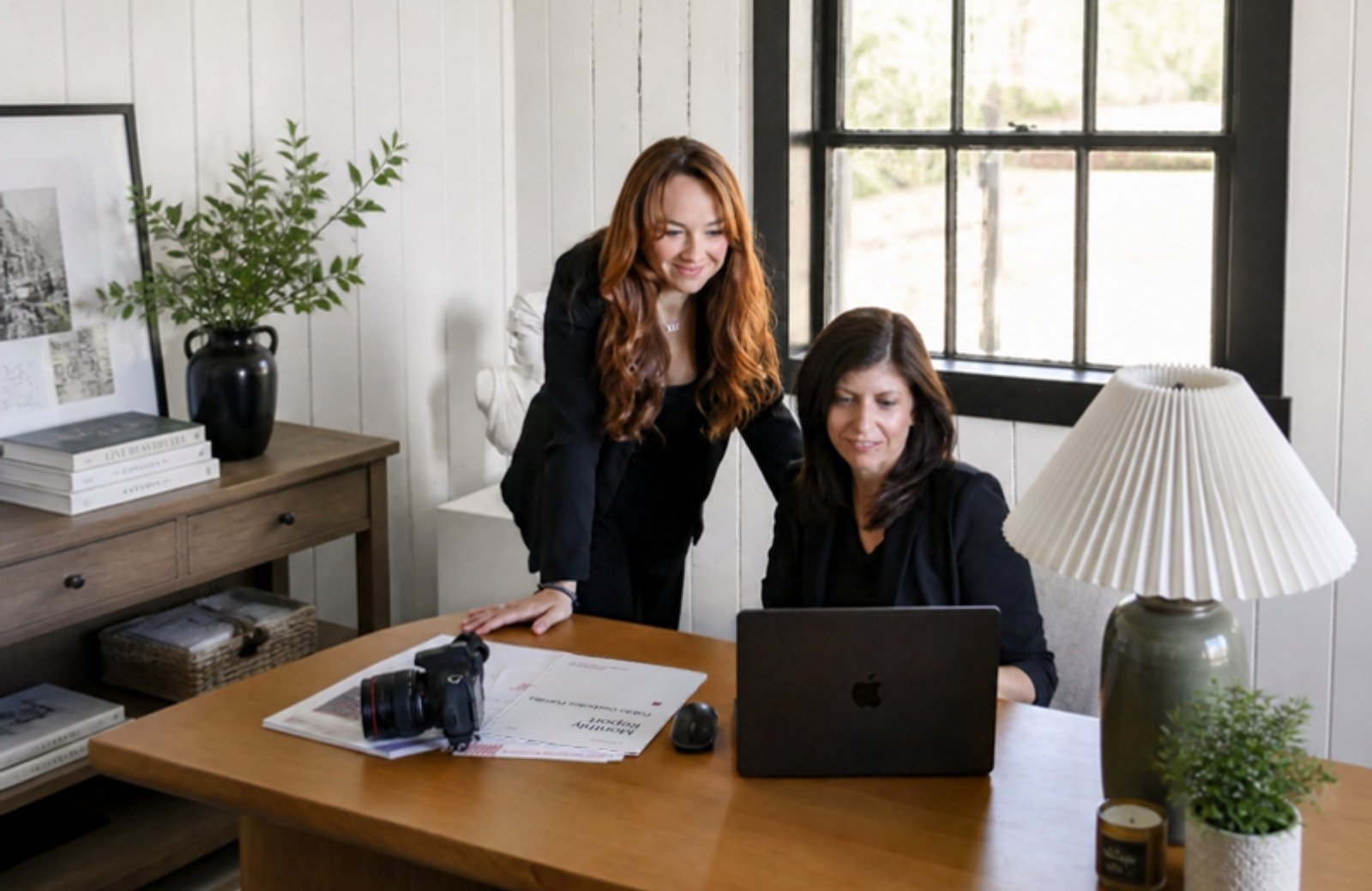One Eleven Creatives co-founders Veronica Dunn and Sarah Newcomb working on client marketing together at a desk with a laptop and camera